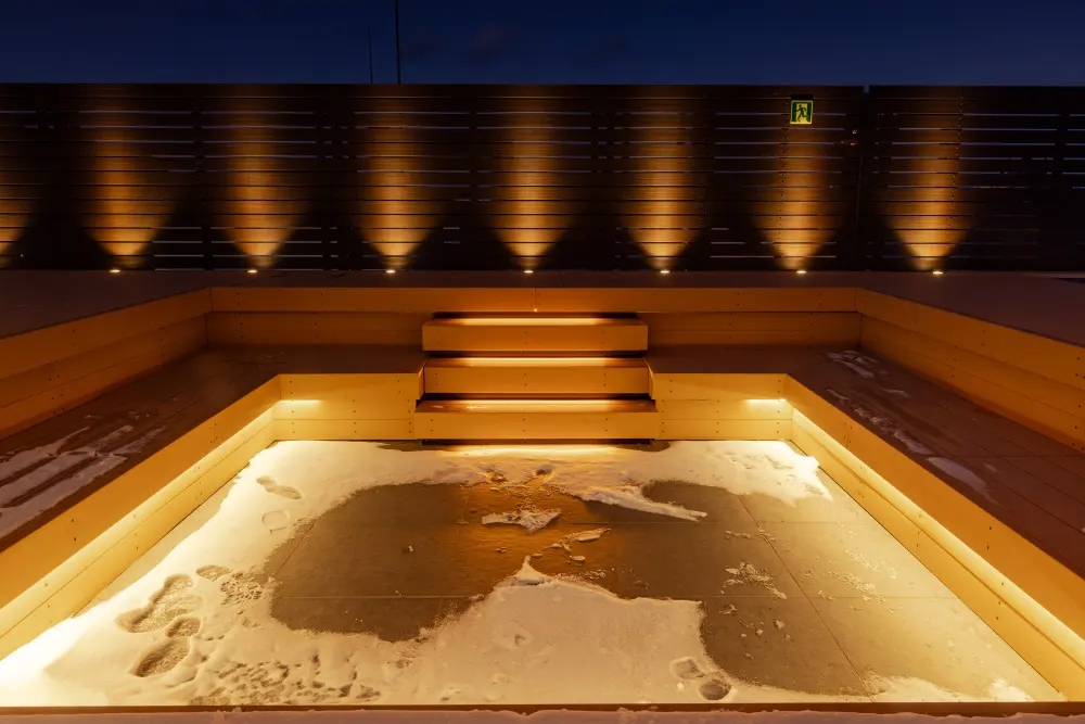 屋上サウナエリアの外気浴スペース内のウッドデッキとフェンスの演出